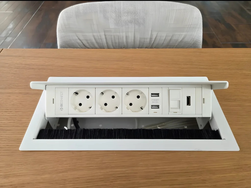 Caja de conexiones IB Connect blanca con enchufes, USB, red y HDMI en una mesa de roble
