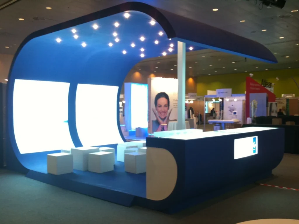 Stand de feria con estructura curva lacada en azul, paneles retroiluminados y mostrador