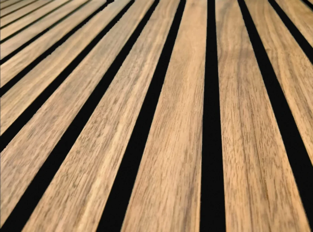 Walnut slat panel on a black background, with even grooves and the natural grain of the wood