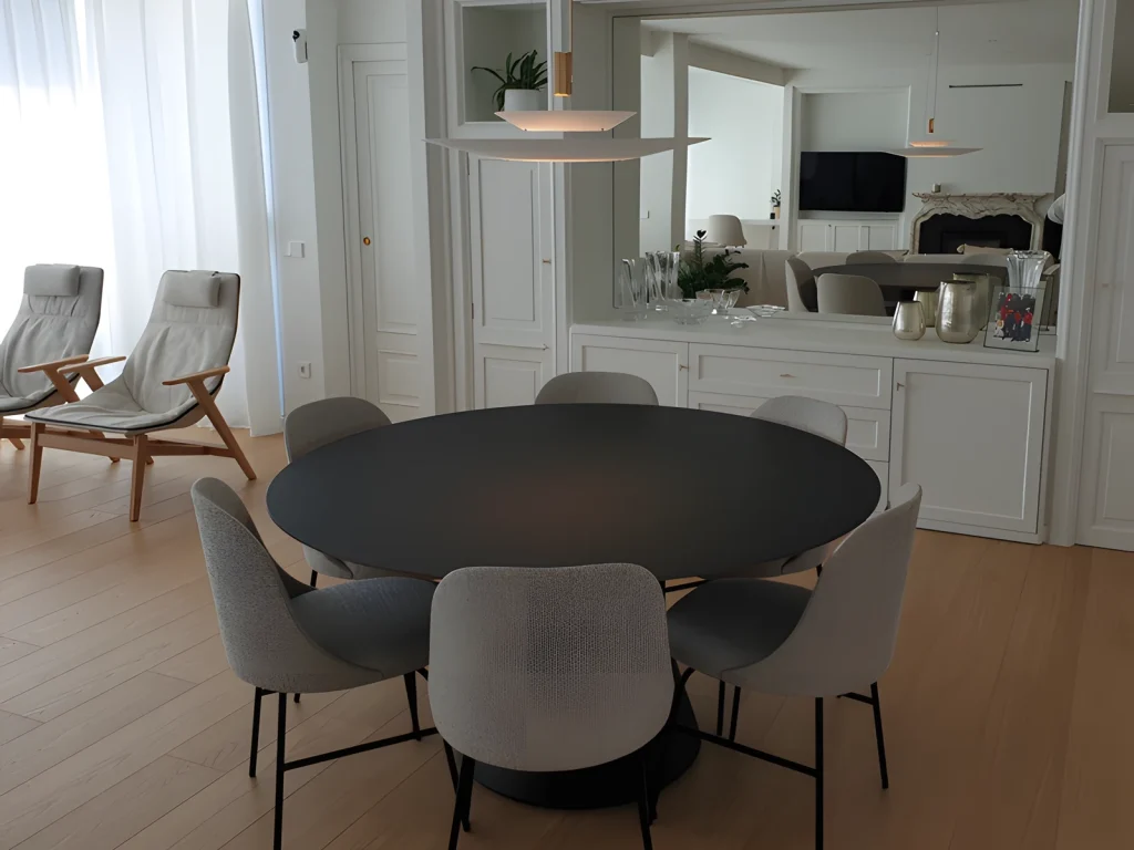 Round table with a black FENIX top and central base, with upholstered chairs