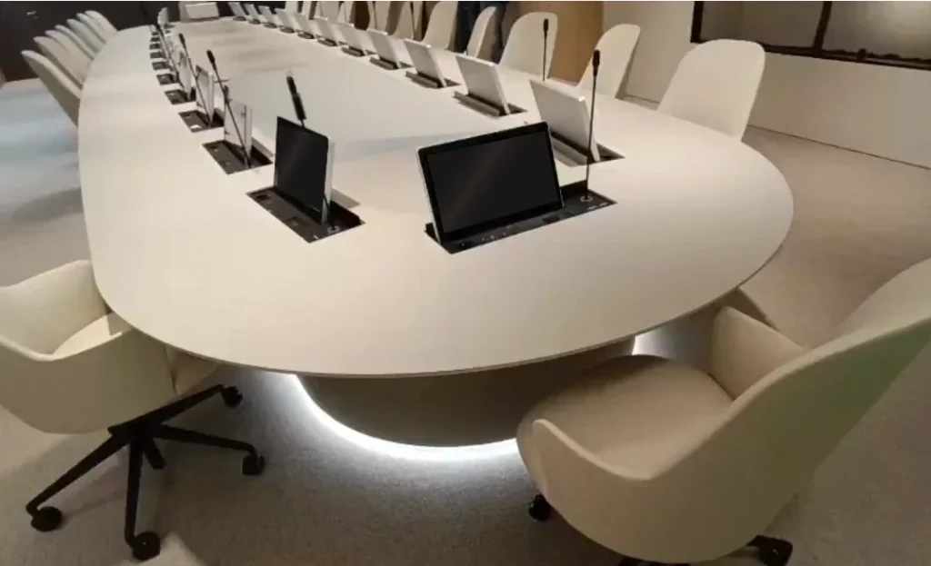 Custom oval boardroom table with pop-up monitors and a microphone at every seat, made by Eban Premium