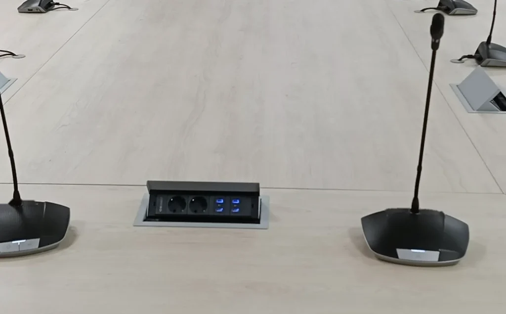 Flush joint between two modules of a boardroom table, with a connection box and microphones, made by Eban Premium
