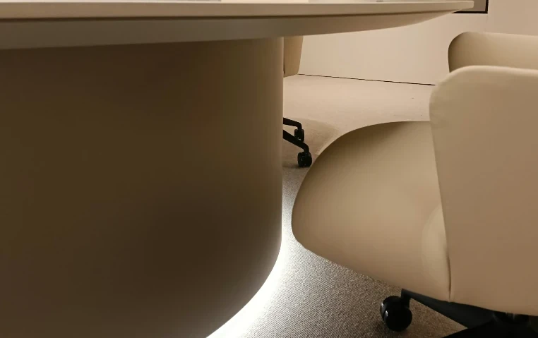 Slim top edge and backlit pedestal of an oval boardroom table