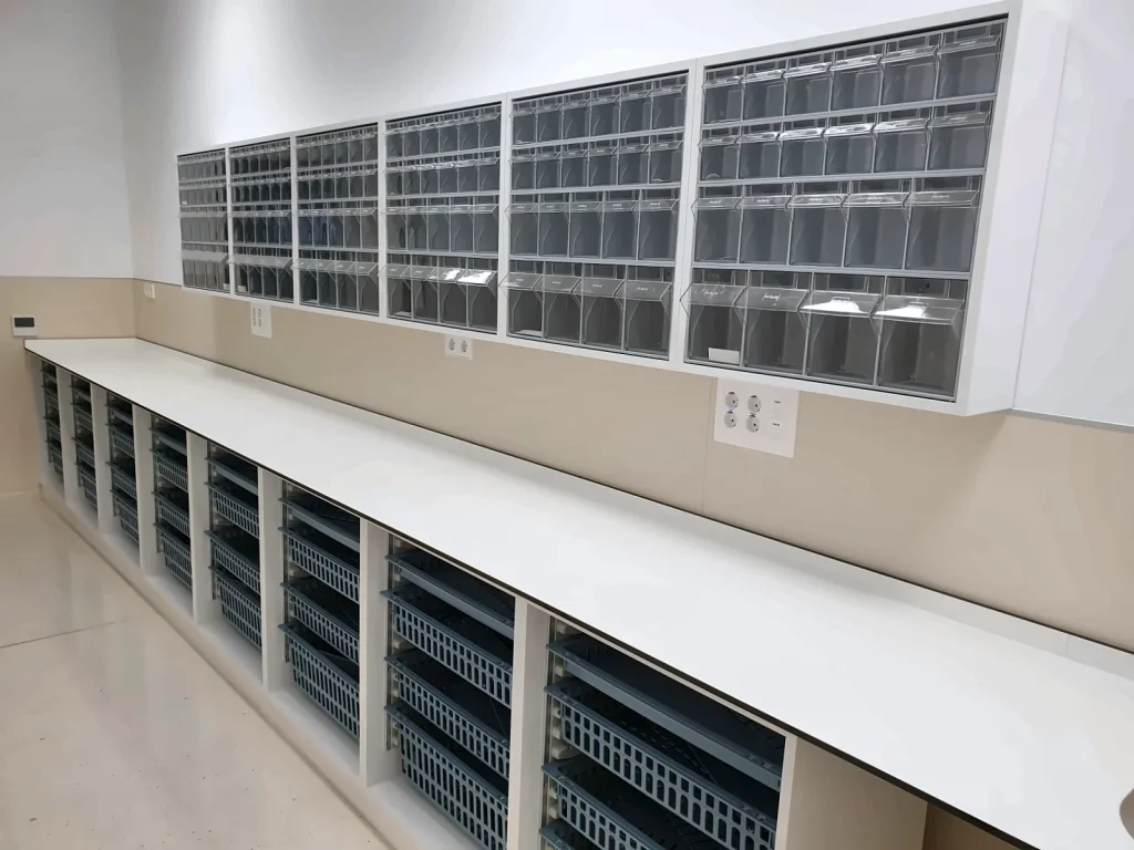 Continuous white phenolic compact worktop over units with baskets, below bin cabinets, in a hospital