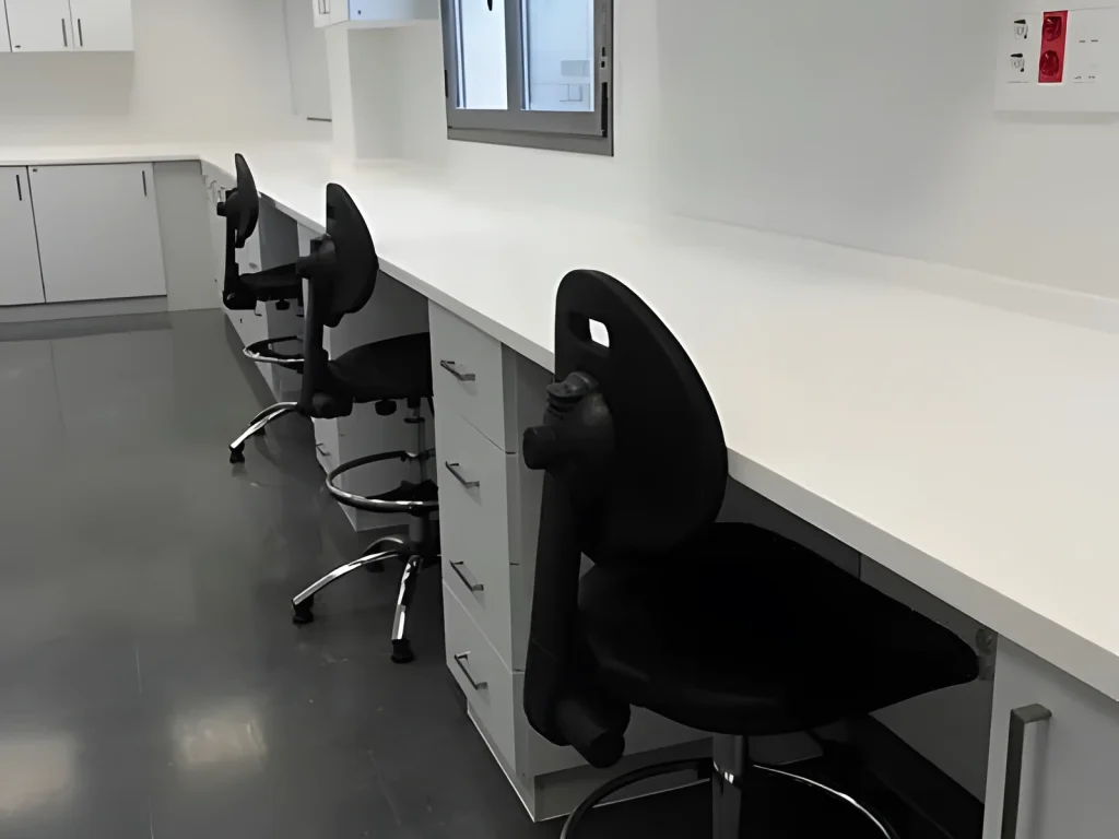 Bancada de laboratorio hospitalario con encimera corrida blanca, cajoneras y armarios altos