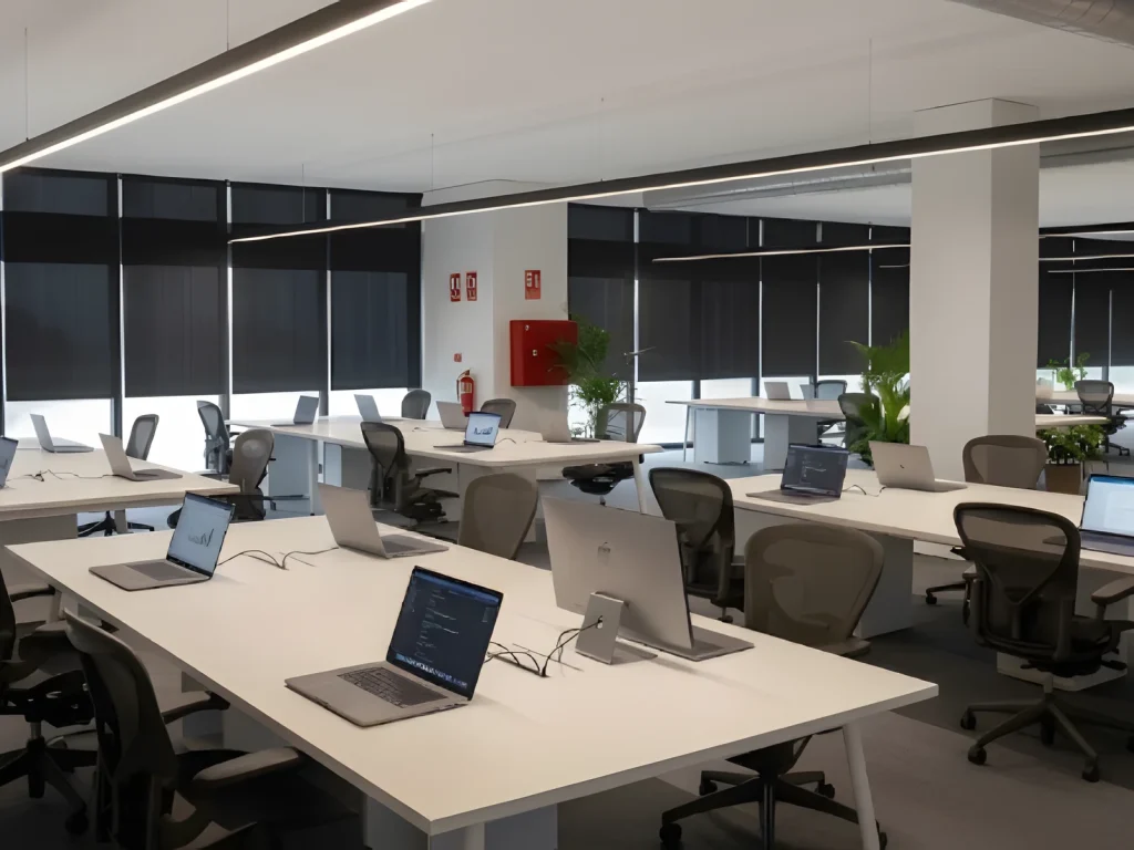 Planta de oficinas con mesas bench blancas y puestos de trabajo en una sede corporativa