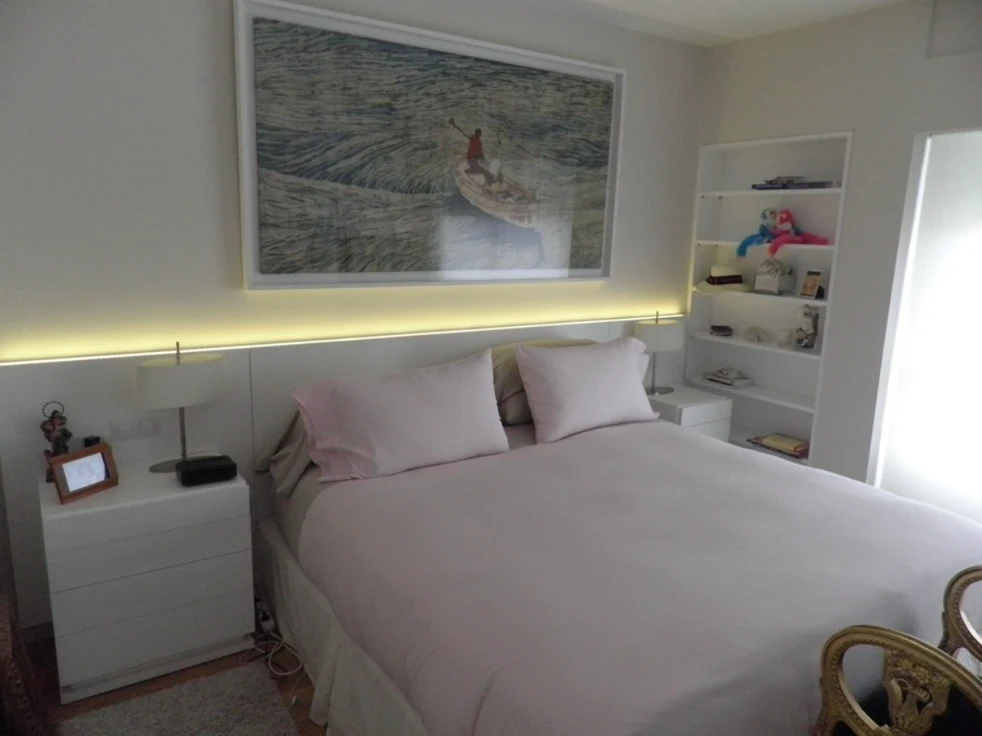 Dormitorio con cabecero lacado en blanco con luz LED integrada, mesillas y librería a medida