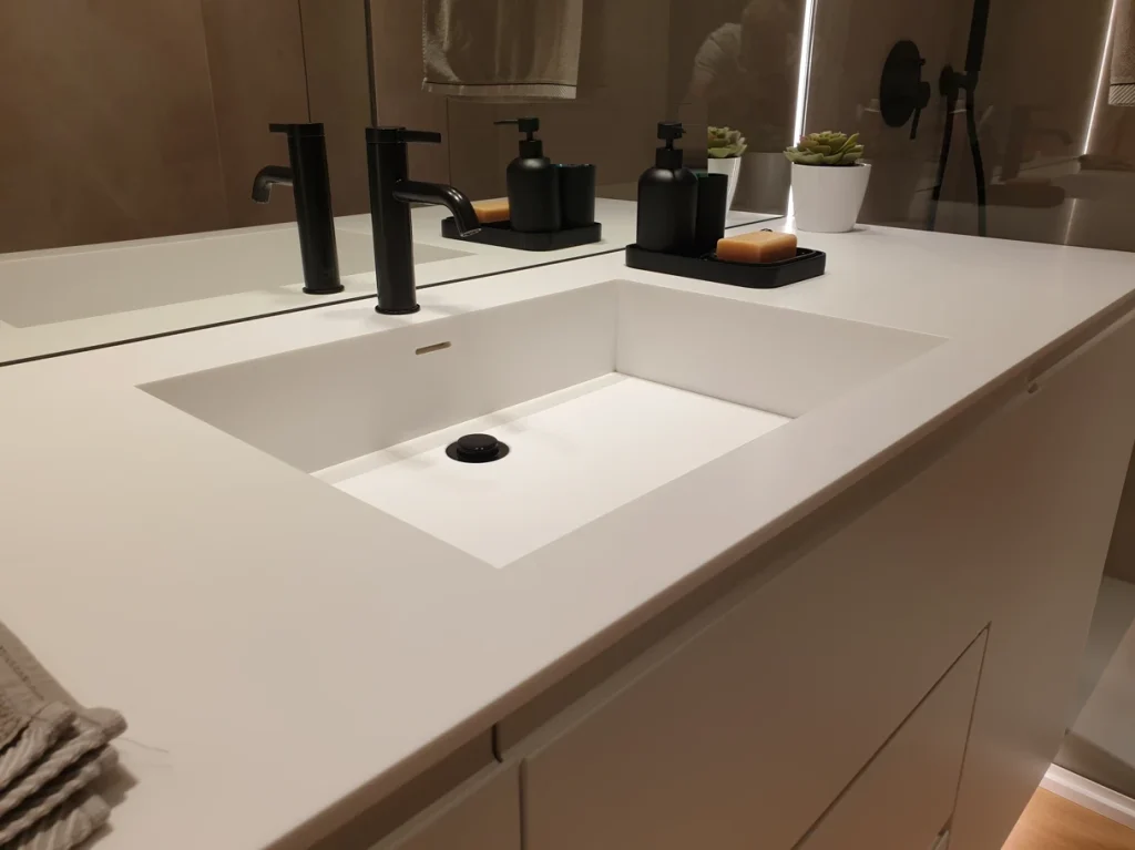 Encimera de baño de solid surface con lavabo integrado y muebles lacados en blanco
