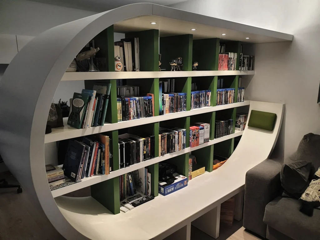 Librería lacada en blanco con baldas verdes y marco curvo que se prolonga en un banco de lectura con cojín, en una vivienda