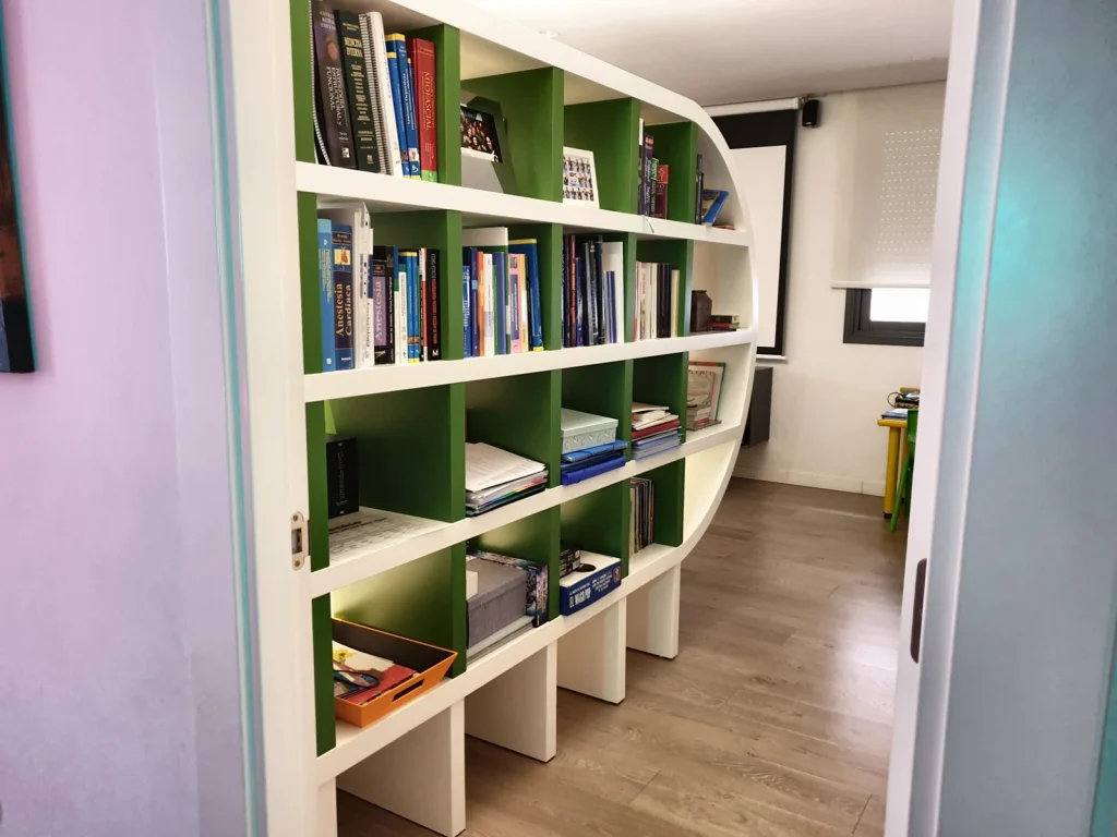 Freestanding white and green lacquered bookcase with a curved end, dividing two areas of a home