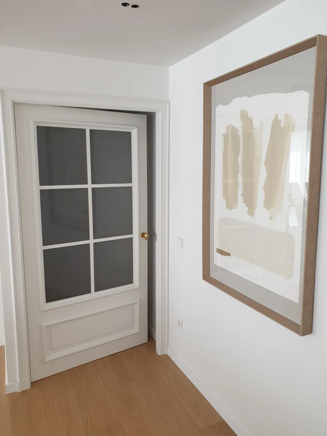 Puerta de paso lacada en blanco con vidriera de seis cuarterones, moldura inferior y pomo de latón