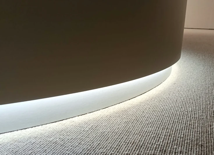 Detail of a curved pedestal with perimeter LED lighting at the base of a meeting table